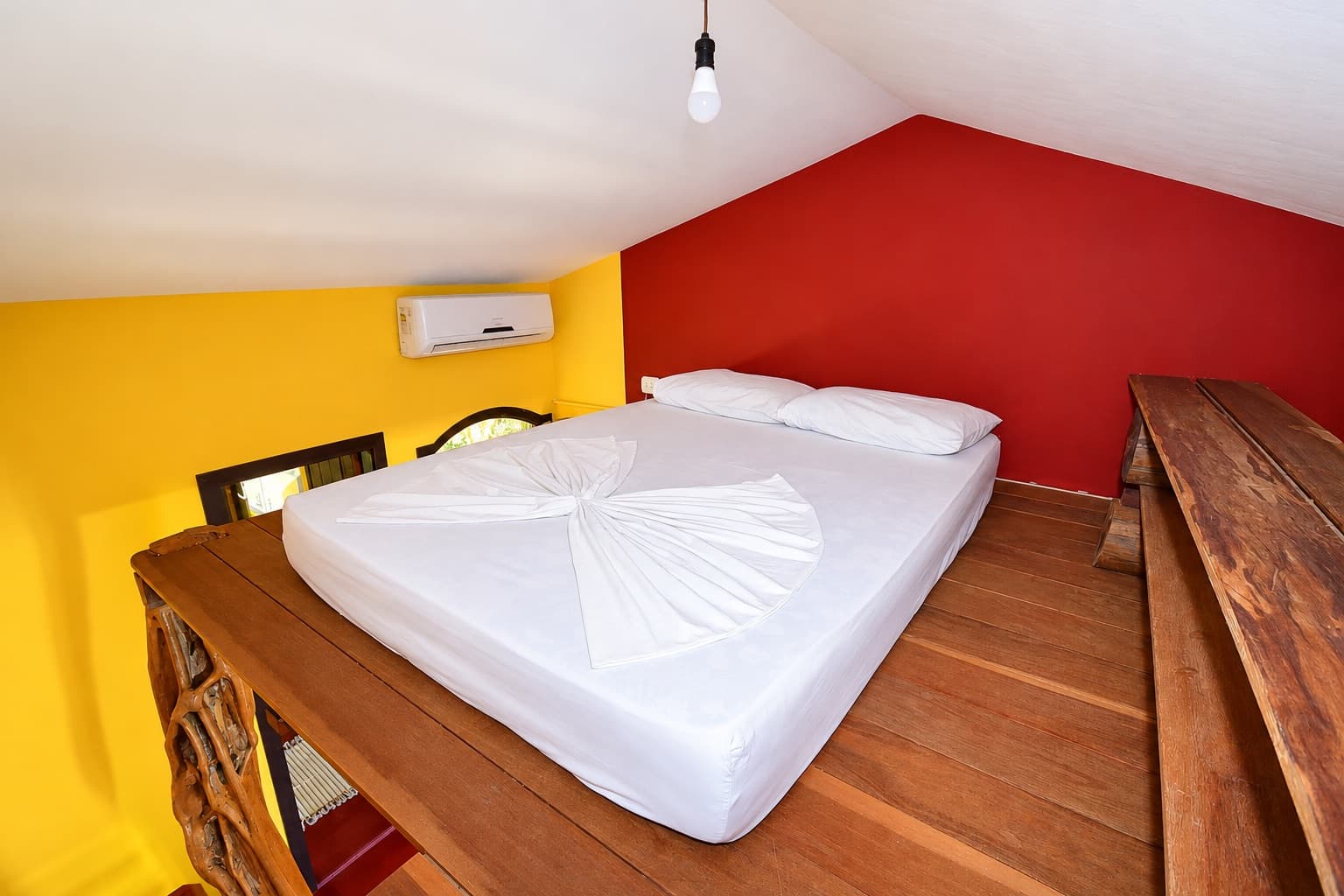Quarto do Chalé, com paredes amarela e vermelha e ar-condicionado